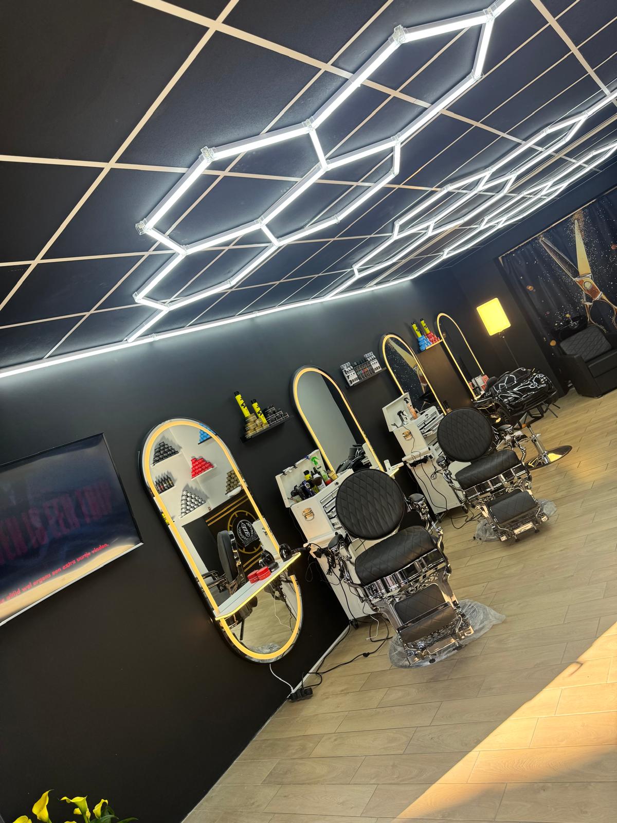Barberstoelen en moderne plafondverlichting bij Barbershop De Rijn